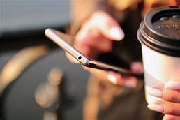 person holding mobile phone and coffee